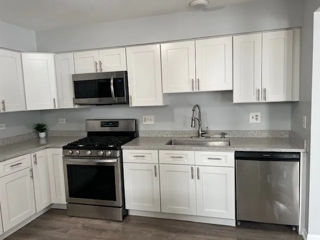 a kitchen with white cabinets and appliances