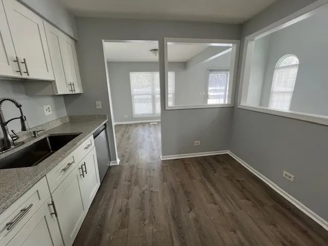 a kitchen with wooden floors and white cabinets