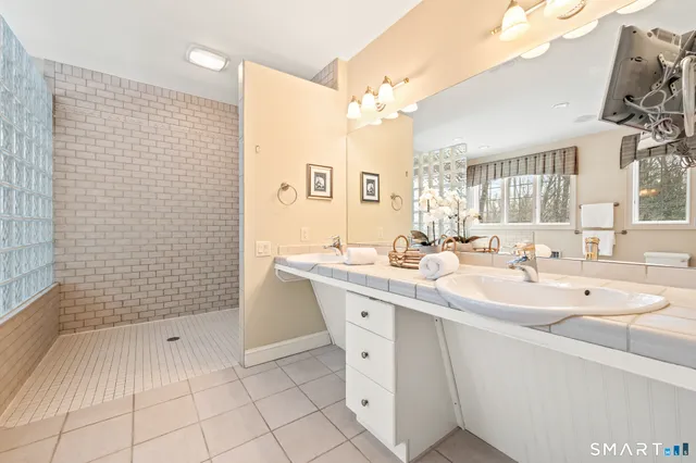 a bathroom with a sink a toilet a mirror and shower