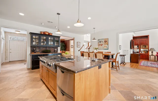 a kitchen with stainless steel appliances granite countertop a stove and a view of living room