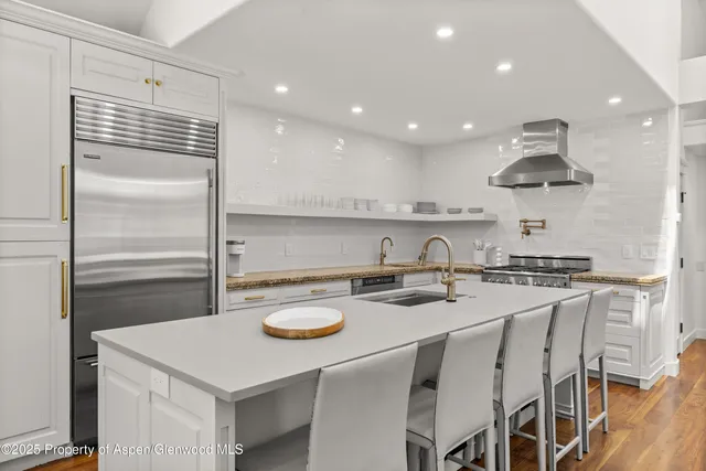 a kitchen with kitchen island stainless steel appliances a sink a stove a refrigerator and cabinets