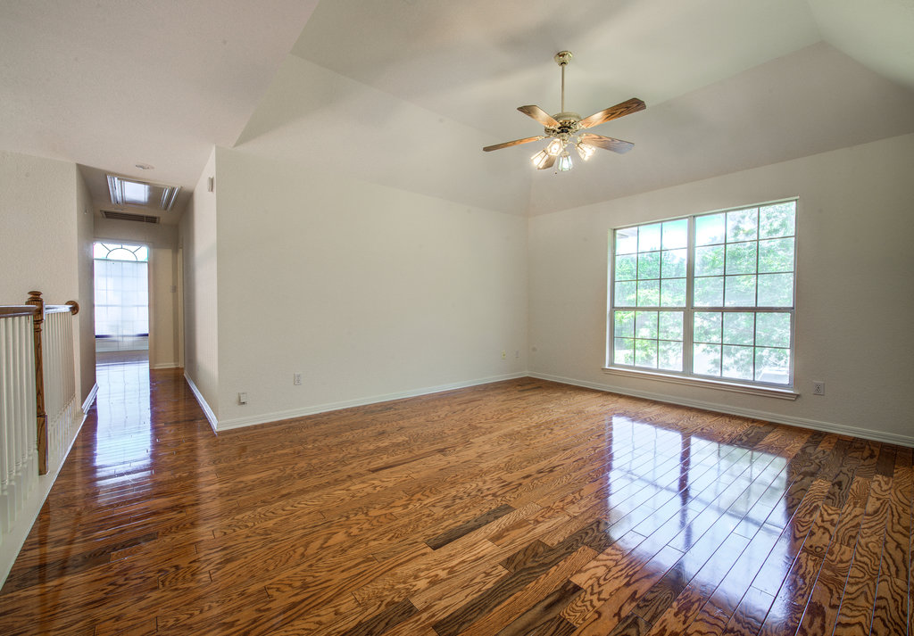 8317 Pommel Drive Austin, TX 78759 - Photo 15 of 26 Natural light floods this spacious living area, showcasing polished hardwood flooring and a high vaulted ceiling.