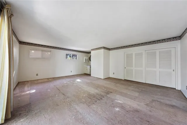a view of an empty room with cabinet and a window