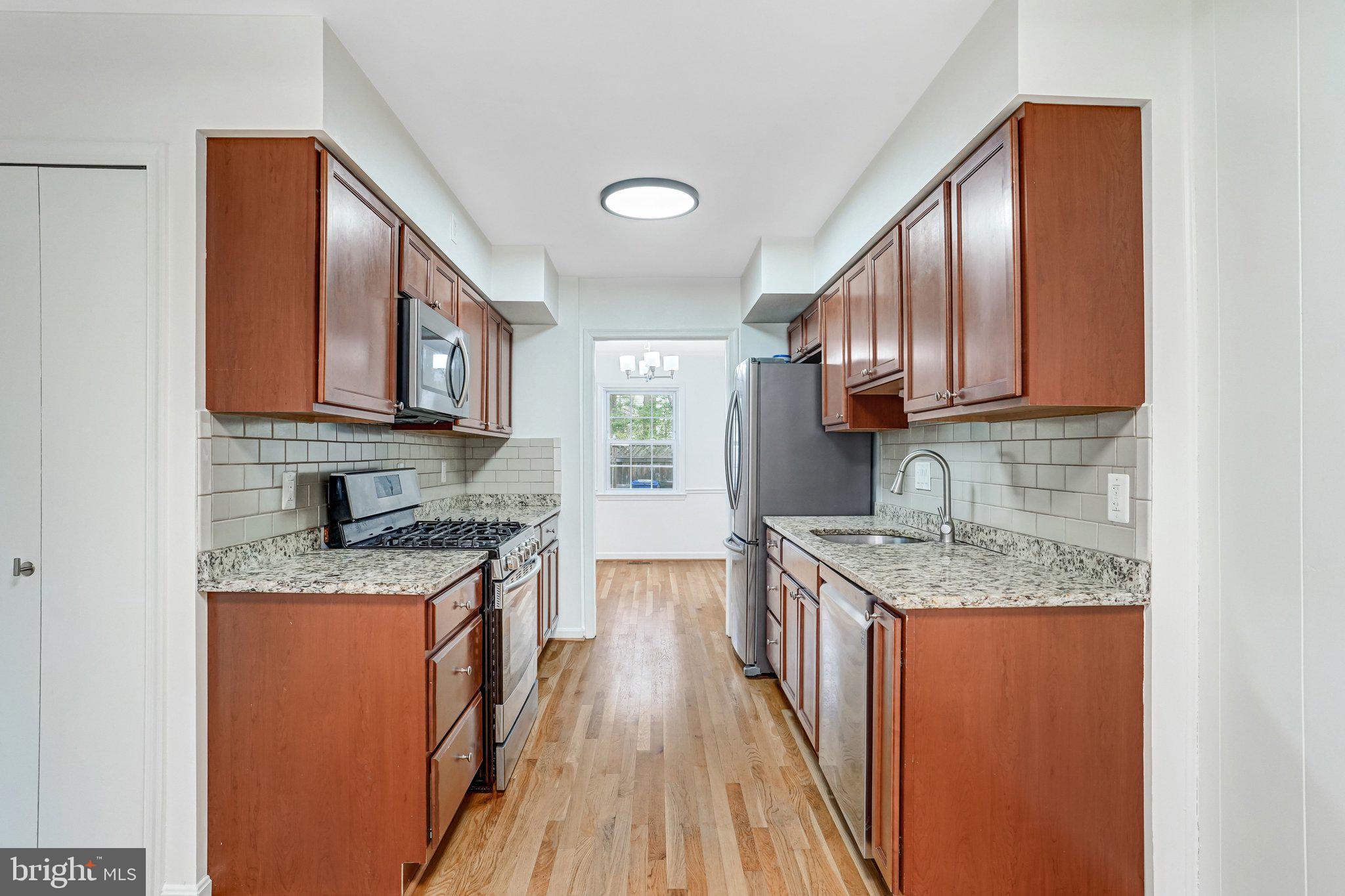9752 Cardinal Road Fairfax, VA 22030 - Photo 7 of 37 a kitchen with stainless steel appliances granite countertop wooden cabinets a stove top oven a sink and dishwasher