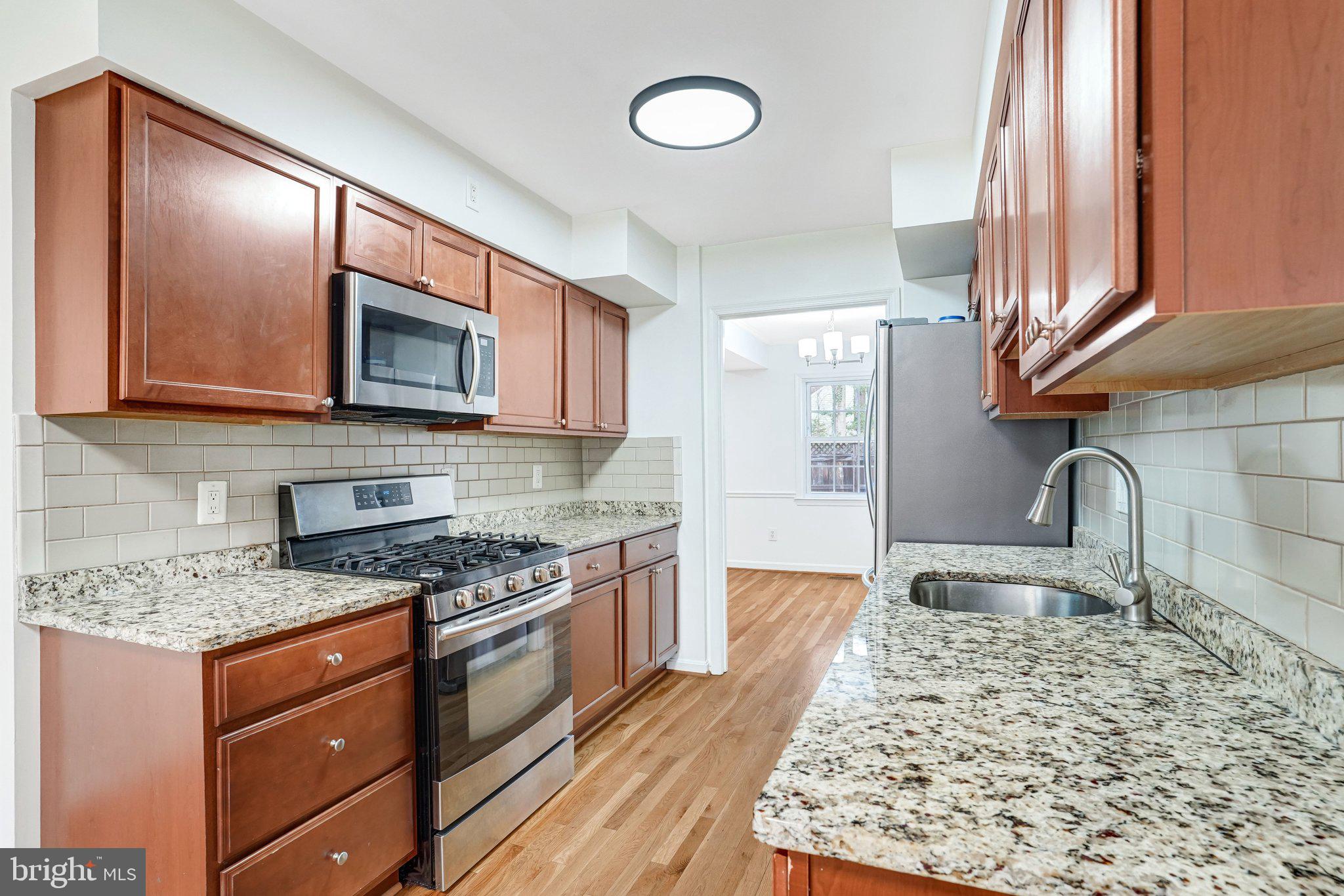 9752 Cardinal Road Fairfax, VA 22030 - Photo 8 of 37 a kitchen with stainless steel appliances granite countertop a sink stove microwave and cabinets