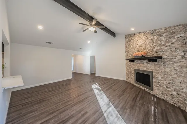 an empty room with wooden floor a fireplace and windows