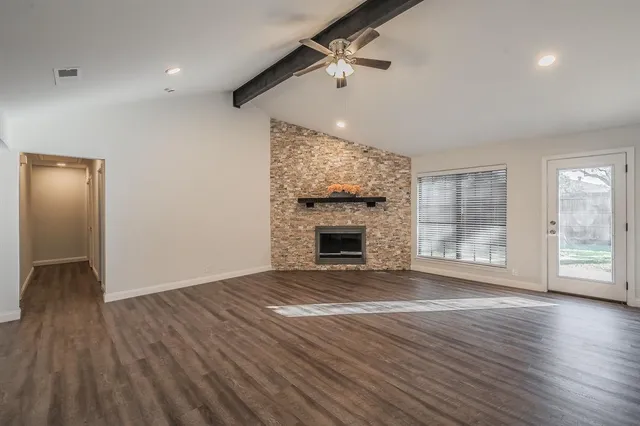 a view of an empty room with wooden floor fireplace and a window