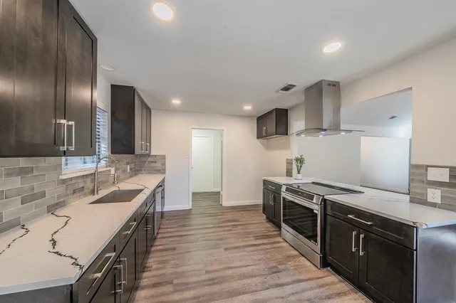 a large kitchen with stainless steel appliances granite countertop a lot of counter space and wooden floor