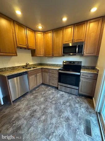 a kitchen with stainless steel appliances granite countertop a stove top oven a sink dishwasher a refrigerator and cabinets with wooden floor