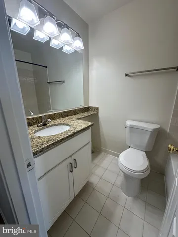 a bathroom with a granite countertop toilet and a sink