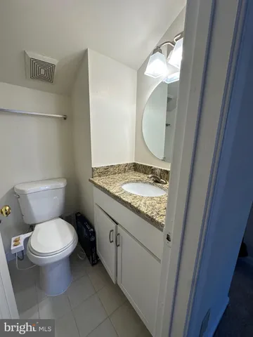 a bathroom with a granite countertop toilet sink and mirror