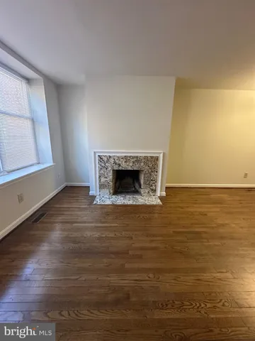 a view of an empty room with wooden floor and a fireplace