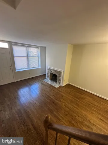 a view of empty room with wooden floor and fireplace