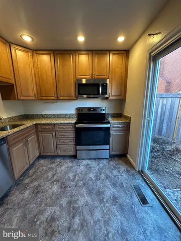 a kitchen with granite countertop a sink a stove a refrigerator and cabinets