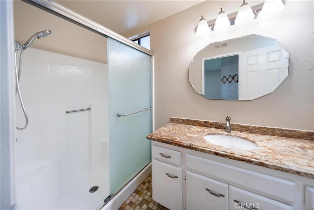 39739 Old Carriage Road Murrieta, CA 92563 - Photo 24 of 31 a bathroom with a granite countertop sink a mirror and a shower