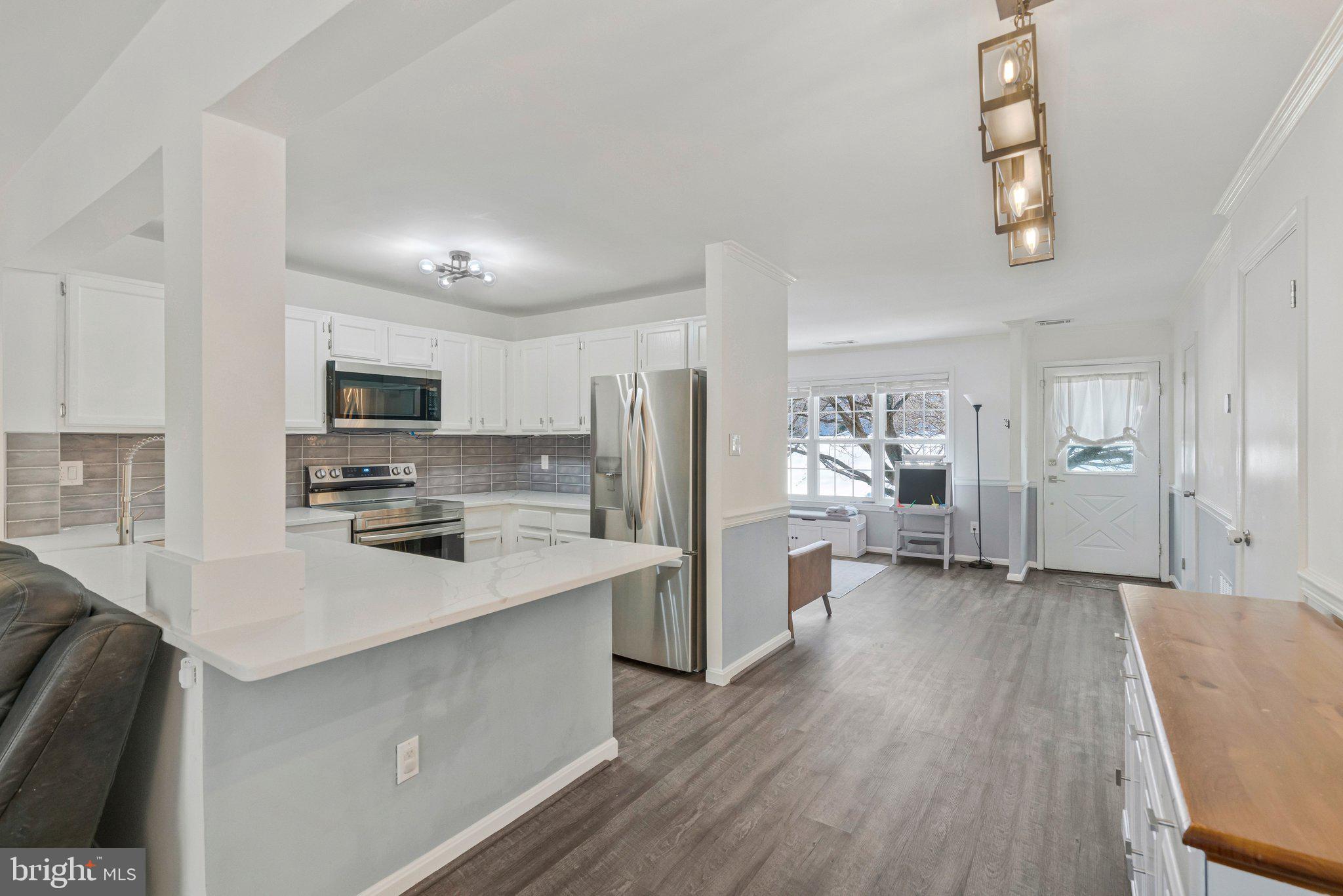 6064 Old Landing Way Burke, VA 22015 - Photo 17 of 38 a kitchen with stainless steel appliances a refrigerator a stove a sink dishwasher and a microwave with wooden floor