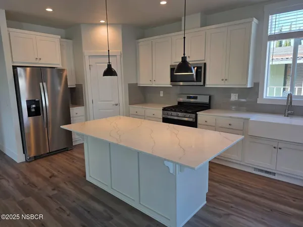 a kitchen with stainless steel appliances granite countertop a refrigerator a stove a sink and a microwave