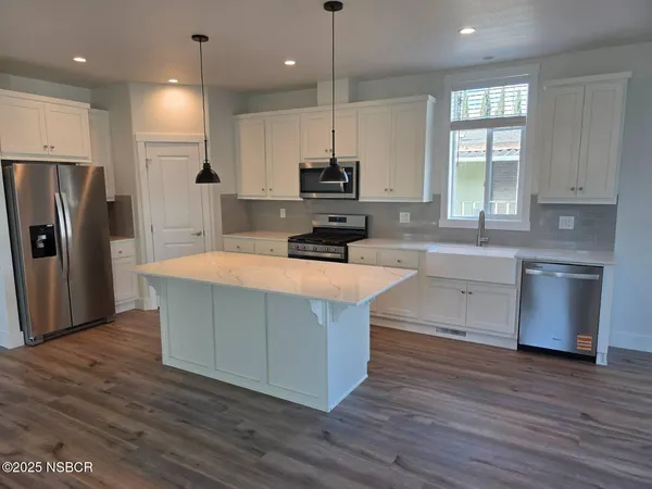 a kitchen with stainless steel appliances granite countertop a sink a stove a refrigerator and island with wooden floor
