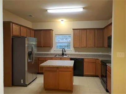 a kitchen with stainless steel appliances granite countertop a sink stove refrigerator and cabinets