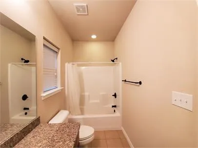 a bathroom with a granite countertop bathtub shower sink vanity and toilet