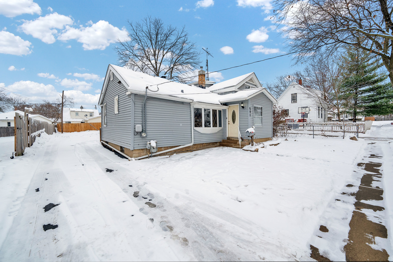 541 Charles Street Aurora, IL 60506 - Photo 5 of 38 a view of a white house with a yard covered in snow