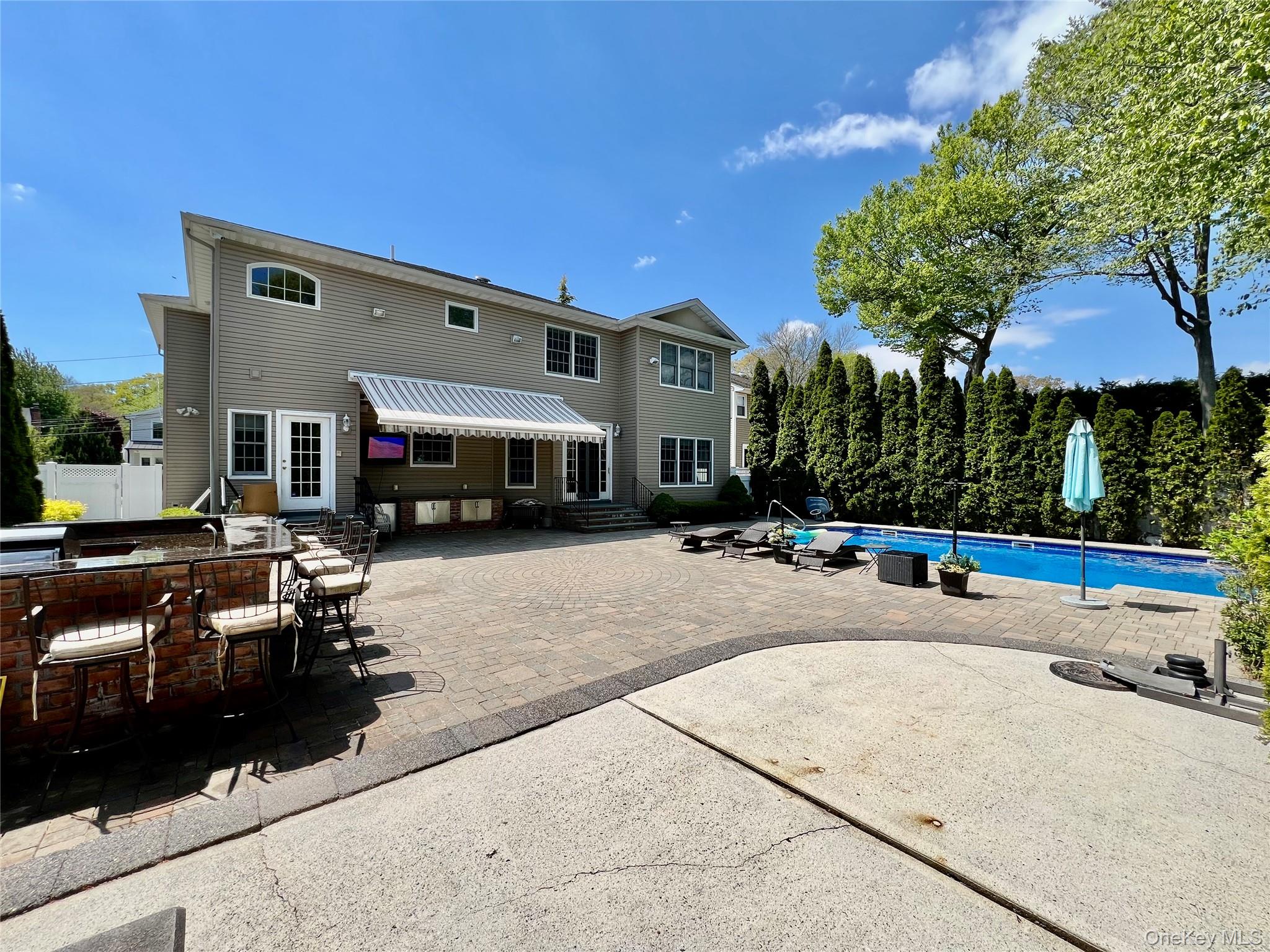 3683 Orchard Road Wantagh, NY 11793 - Photo 41 of 42 a view of a patio with table and chairs under an umbrella with large trees