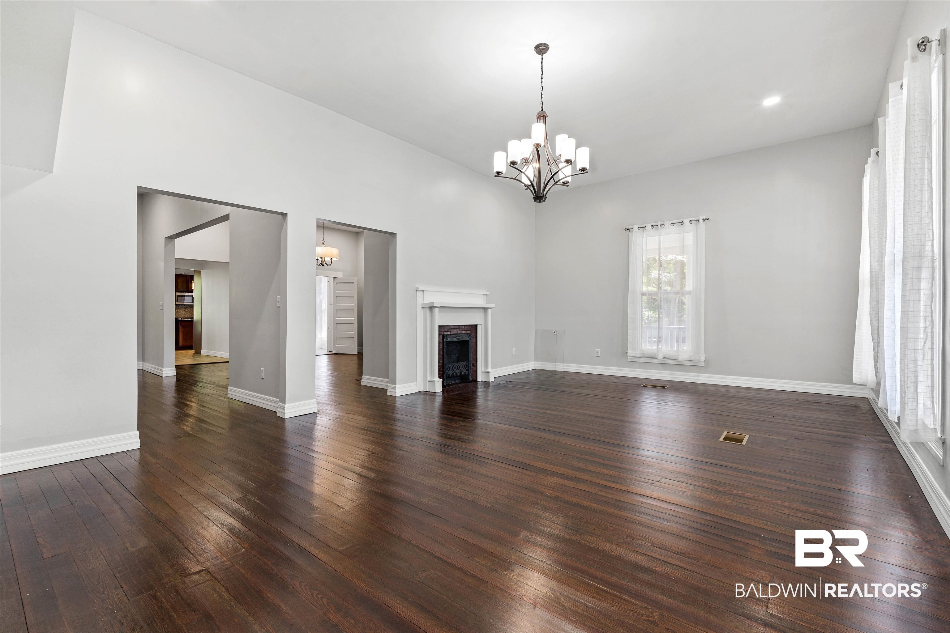 407 East 2nd Street Bay Minette, AL 36507 - Photo 5 of 40 Unfurnished living room featuring dark wood-style floors, a chandelier, a fireplace with flush hearth, and recessed lighting