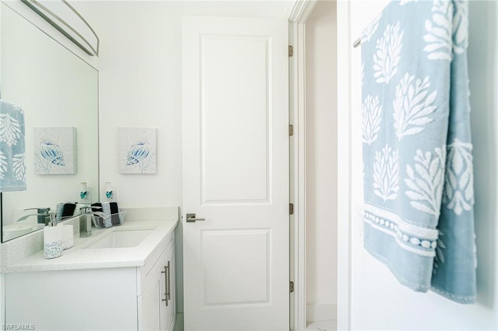 907 Homestead Road South Lehigh Acres, FL 33974 - Photo 26 of 43 White vanity with shaker-style cabinetry, an integrated sink, and a light-toned countertop