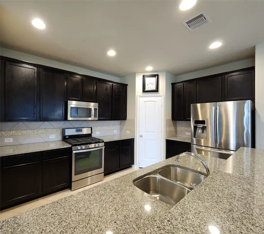 a kitchen with stainless steel appliances granite countertop a sink stove and refrigerator
