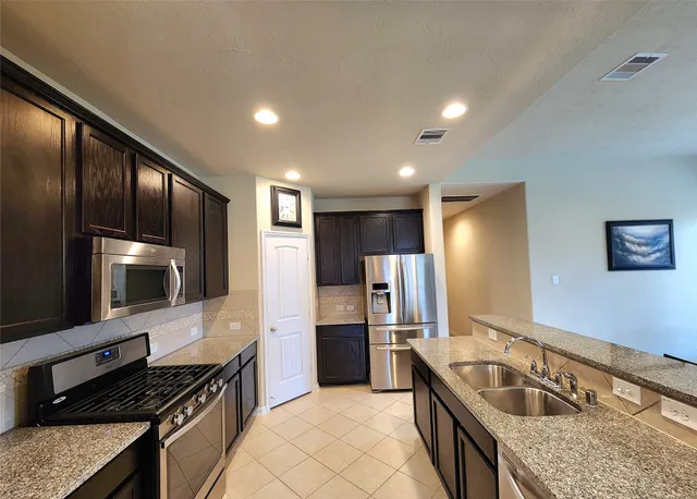 a kitchen with granite countertop stainless steel appliances cabinets a sink and a counter top space