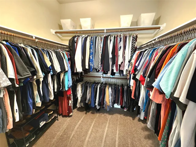 a view of walk in closet with clothes and shoes