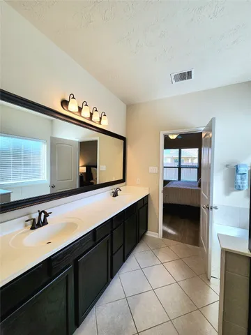 a en suite bathroom with a double vanity sink and a large mirror