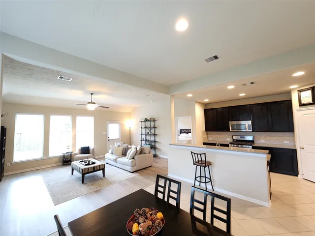 a living room kitchen with a dining table chairs and a dining table with kitchen view