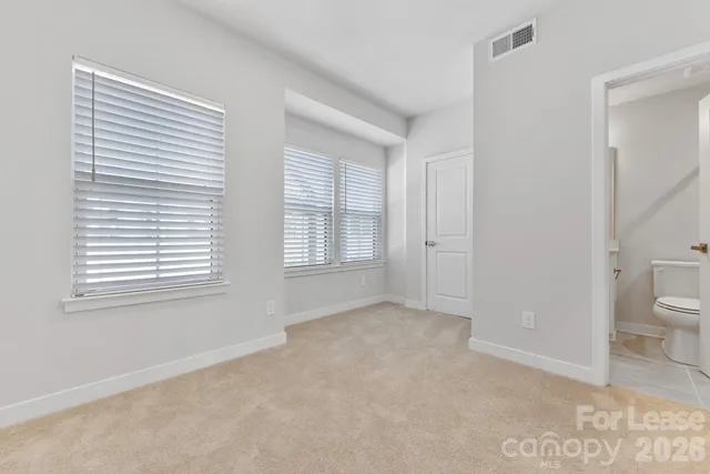 a view of an empty room with a window and bathroom