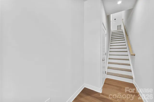 a view of a hallway with stairs and wooden floor