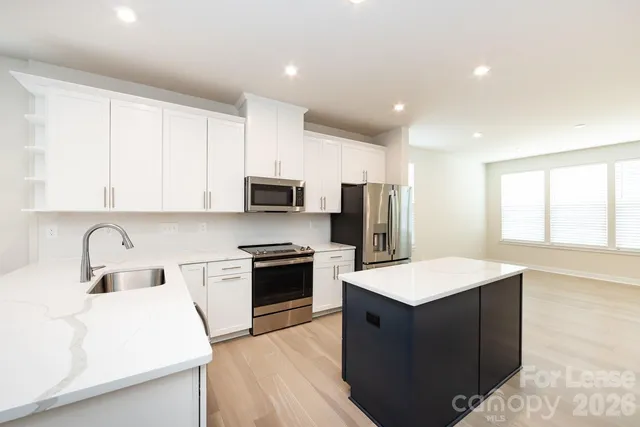 a open kitchen with stainless steel appliances granite countertop a sink dishwasher stove top oven and refrigerator