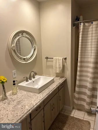 a bathroom with a granite countertop sink a mirror and shower