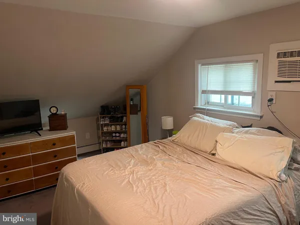 a bedroom with a bed and a flat tv screen on the dresser