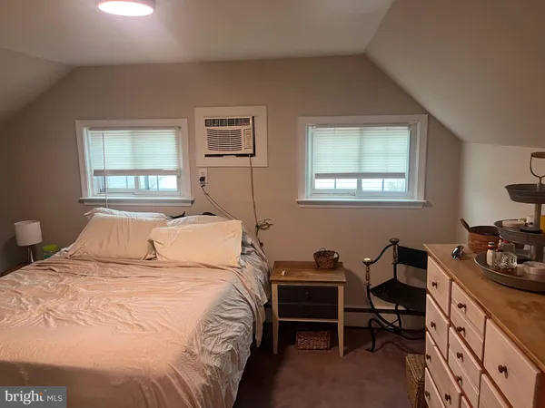 a bedroom with a bed and a dresser next to a window