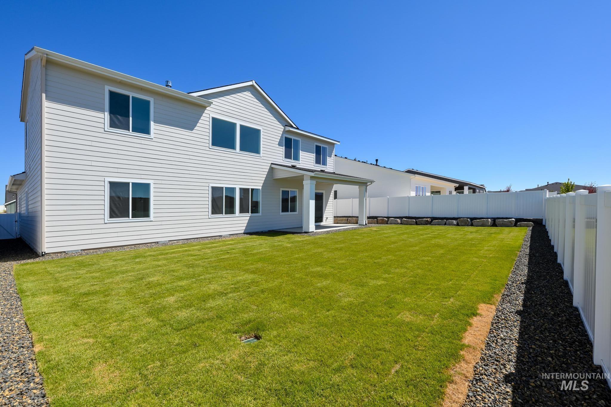14703 Serenity Pt Street Caldwell, ID 83607 - Photo 33 of 45 Expansive backyard featuring a manicured lawn, full white privacy fencing, and a covered patio area