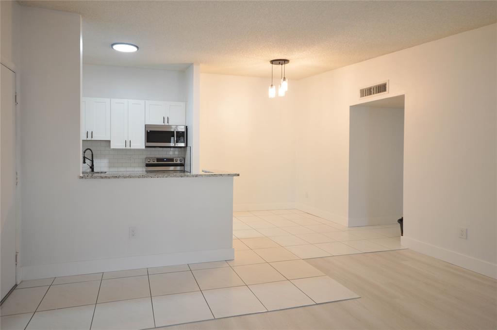 9499 West McNab Road, Unit 208 Tamarac, FL 33321 - Photo 4 of 12 a kitchen with stainless steel appliances a refrigerator sink and microwave