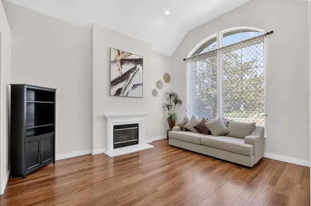 a large kitchen with stainless steel appliances granite countertop a stove a sink a refrigerator and white cabinets with wooden floor