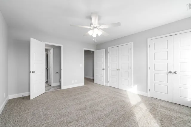 a view of an empty room and chandelier fan