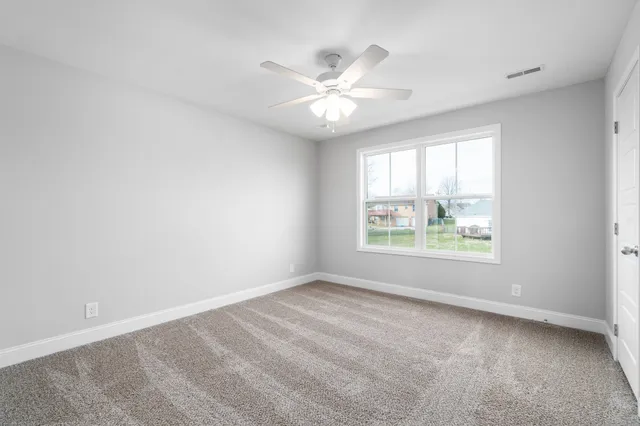 an empty room with windows and ceiling fan