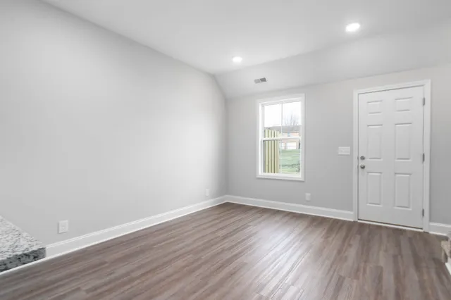 an empty room with wooden floor and windows