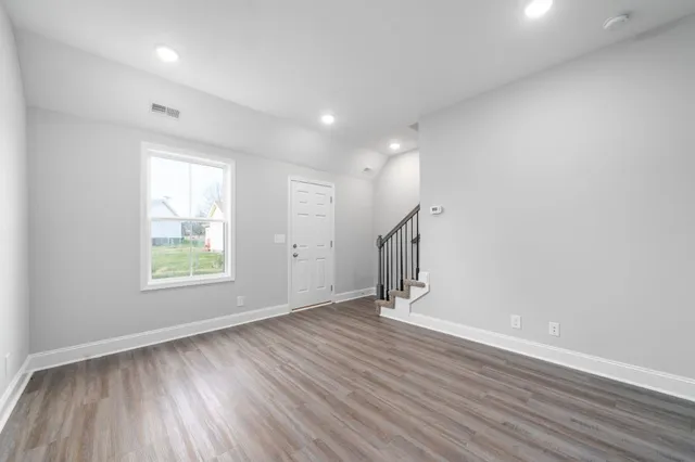 an empty room with wooden floor and windows