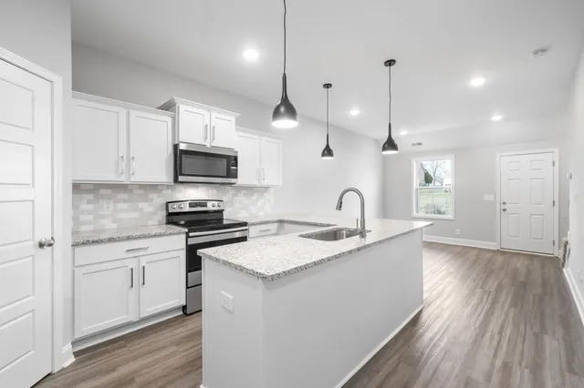 a kitchen with granite countertop a sink a counter space appliances and cabinets