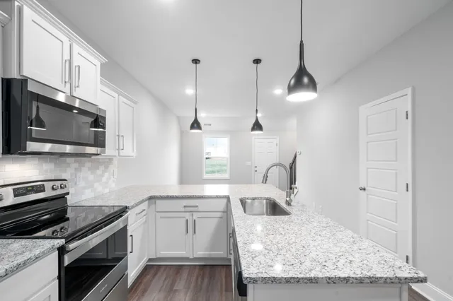 a kitchen with stainless steel appliances granite countertop a sink stove and microwave