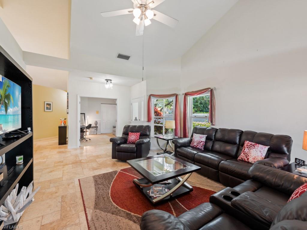 181 Napa Ridge Road East, Unit 35 Naples, FL 34119 - Photo 3 of 17 a living room with furniture a flat screen tv and a chandelier