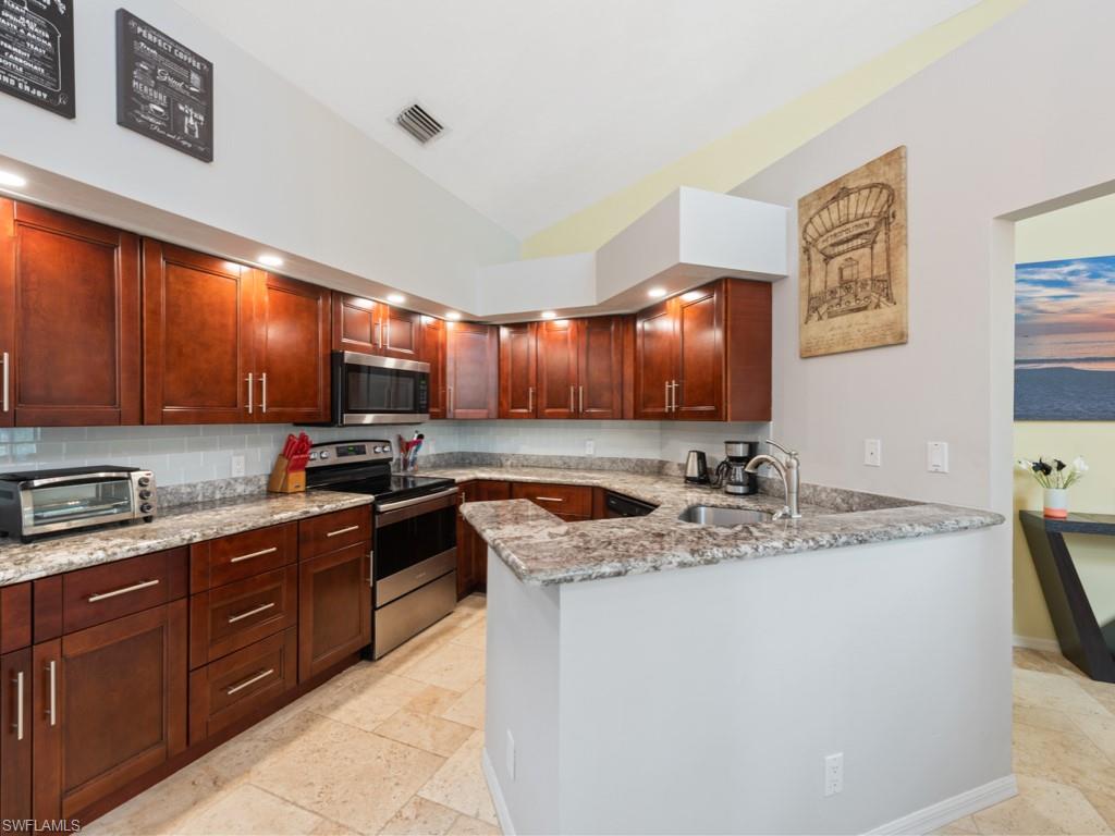 181 Napa Ridge Road East, Unit 35 Naples, FL 34119 - Photo 6 of 17 a kitchen with stainless steel appliances granite countertop a sink stove and cabinets